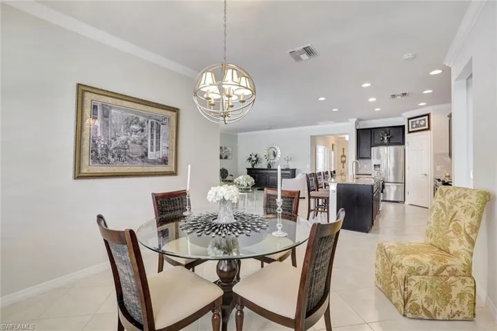 Dining space with a chandelier, visible vents, ornamental molding, and light tile patterned floors