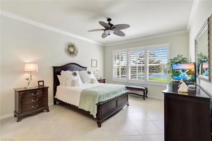 Bedroom with light tile patterned floors, ceiling fan, baseboards, and crown molding
