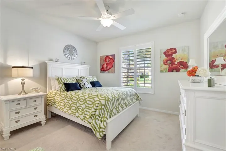 Bedroom with light carpet, ceiling fan, and baseboards
