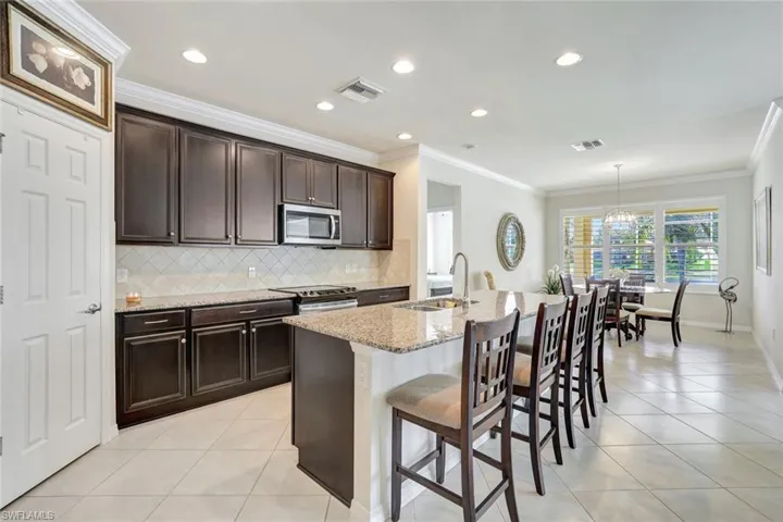 Kitchen with stainless steel appliances, an island with sink, a sink, and visible vents
