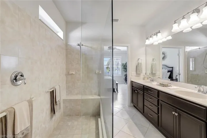 Full bathroom with double vanity, visible vents, connected bathroom, a sink, and walk in shower