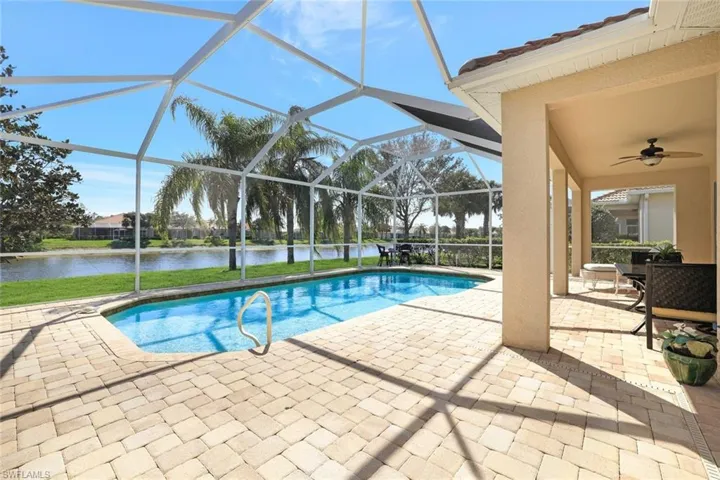 Pool with a ceiling fan, a patio area, glass enclosure, and a water view