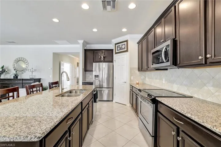 Kitchen with visible vents, an island with sink, stainless steel appliances, a kitchen bar, and a sink