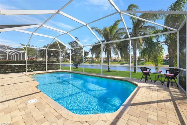 Pool with a lanai, a water view, a patio area, and a lawn