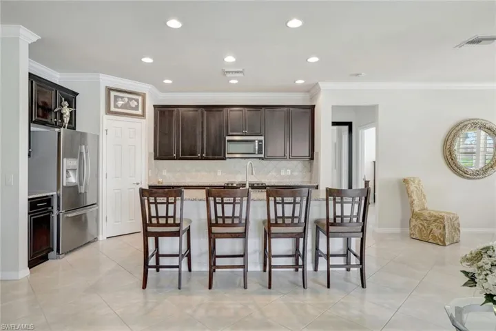 Kitchen featuring appliances with stainless steel finishes, a breakfast bar, a center island with sink, and visible vents