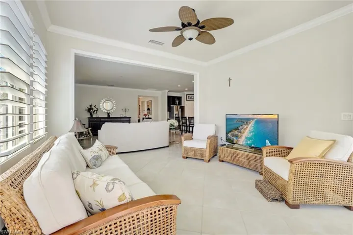 Living room with light tile patterned floors, visible vents, and crown molding