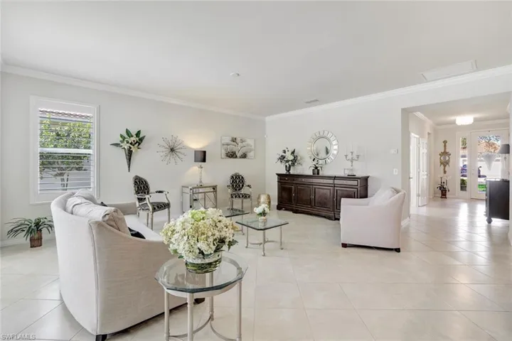 Living area featuring baseboards, ornamental molding, light tile patterned flooring, and a healthy amount of sunlight