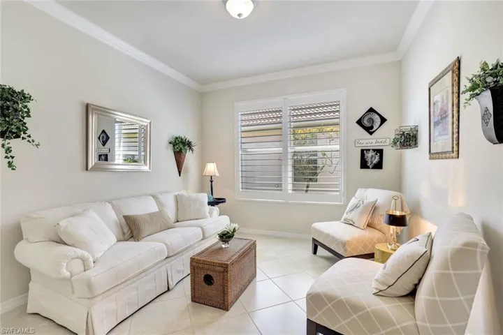 Living room with baseboards, crown molding, and light tile patterned flooring