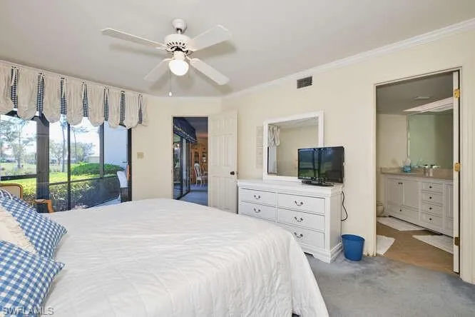 Carpeted bedroom featuring visible vents, a ceiling fan, ensuite bath, ornamental molding, and access to outside