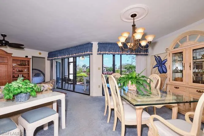 Dining area with carpet flooring, crown molding, and ceiling fan with notable chandelier