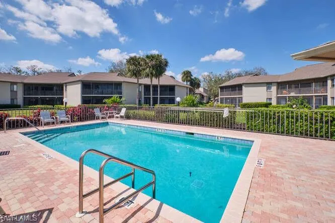 Pool with a patio area, fence, and a residential view