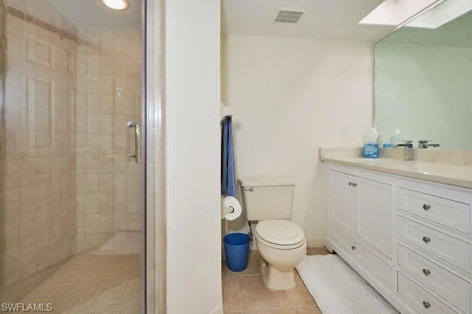 Bathroom with a skylight, visible vents, toilet, a shower stall, and tile patterned flooring