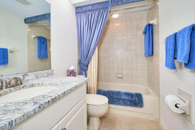 Bathroom with tile patterned flooring, toilet, visible vents, vanity, and shower / bath combo