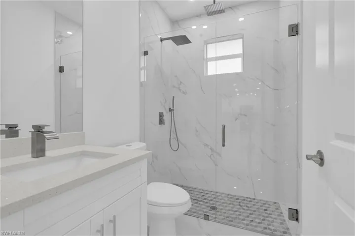 Bathroom with vanity, a marble finish shower, and marble finish floors