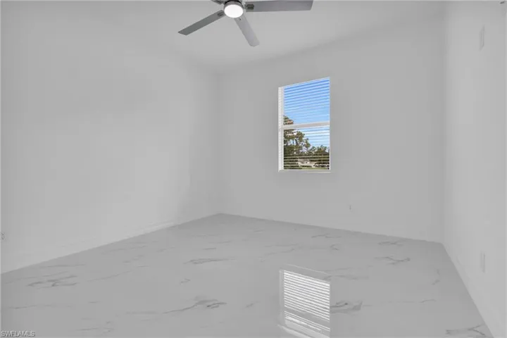 Empty room featuring light marble finish floors and ceiling fan
