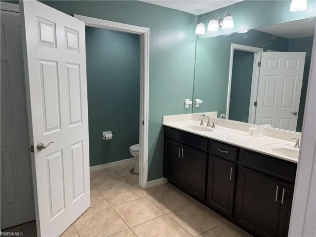 Bathroom featuring a dual vanity with dark wood cabinetry, white countertops, and undermount sinks