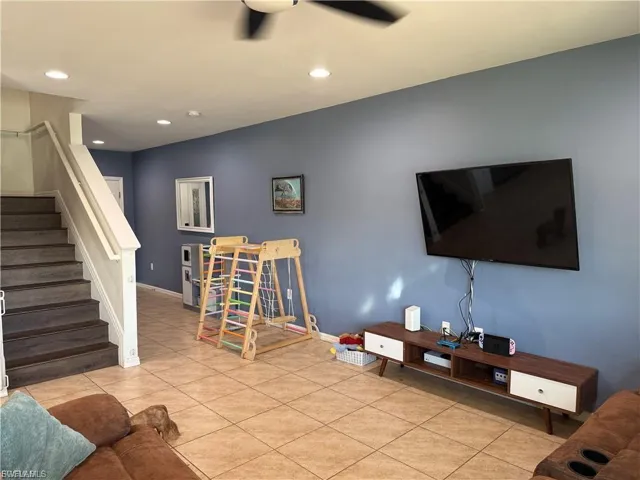 Living area featuring tile flooring and a ceiling fan with integrated lighting
