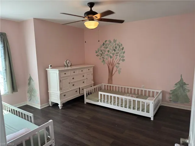 Spacious room featuring wood-finish flooring and a ceiling fan with integrated lighting