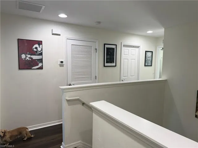 Second-story hallway featuring dark wood-finish flooring, white walls, recessed lighting, and white baseboards
