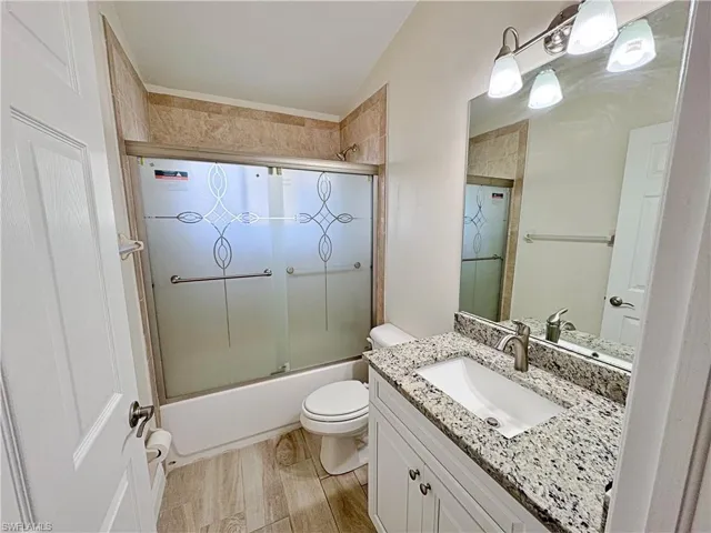 Bathroom featuring vanity, combined bath / shower with glass door, and light wood-type flooring