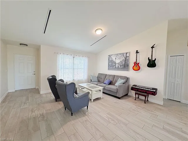 Living room with light wood-type flooring and lofted ceiling