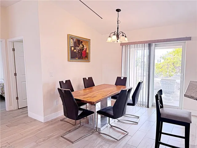 Dining space featuring a chandelier, vaulted ceiling, and wood tiled floors