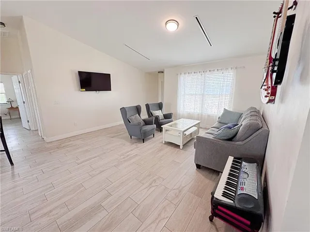 Living room with vaulted ceiling, healthy amount of natural light, and wood tiled floors