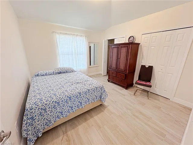 Third Bedroom featuring light wood-style floors, vaulted ceiling, and multiple closets
