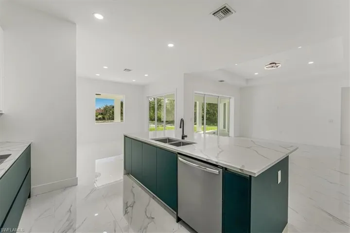 Kitchen with stainless steel dishwasher, green cabinetry, open floor plan, a kitchen island with sink, and recessed lighting