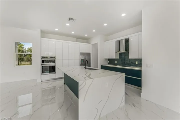 Kitchen featuring modern cabinets, wall chimney exhaust hood, stainless steel appliances, recessed lighting, and white cabinets