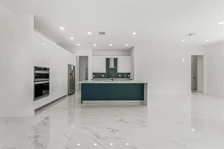 Kitchen with stainless steel appliances, modern cabinets, white cabinetry, backsplash, and recessed lighting