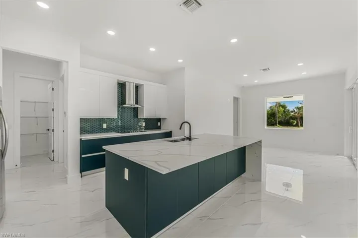 Kitchen with white cabinetry, recessed lighting, modern cabinets, tasteful backsplash, and light marble finish flooring