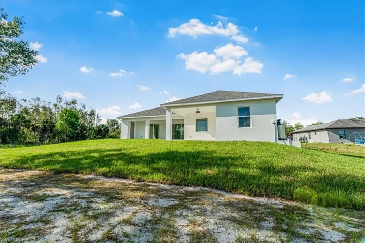 Back of property featuring stucco siding and a yard