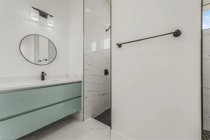 Full bath featuring marble tiled flooring, a marble finish shower, and vanity