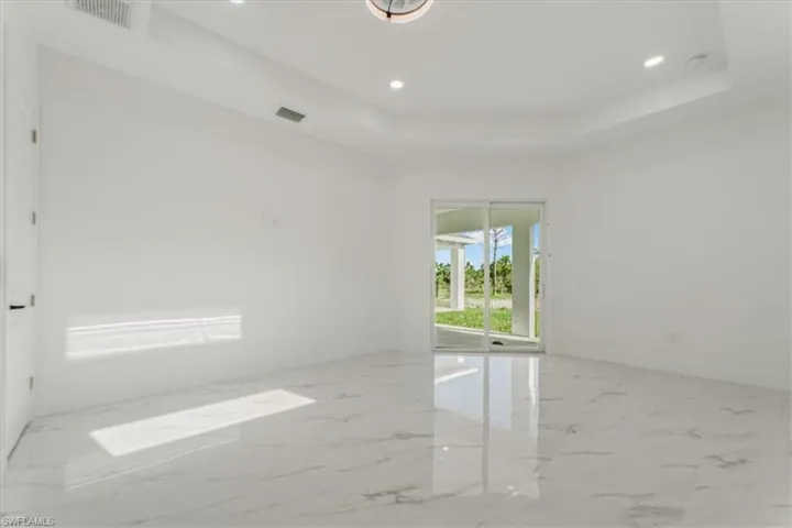 Unfurnished room with recessed lighting, marble finish flooring, and a raised ceiling