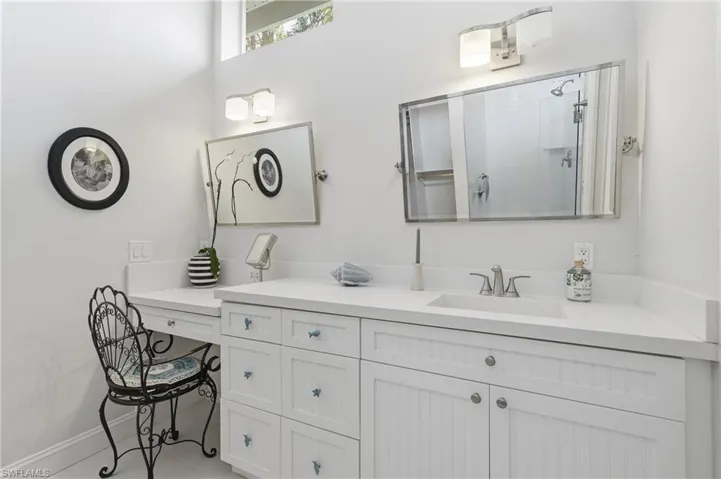 White vanity with integrated sink, brushed nickel faucet, built-in makeup vanity, and upper transom window
