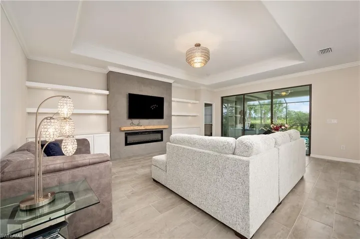 Living room featuring built in shelves, crown molding, and a raised ceiling