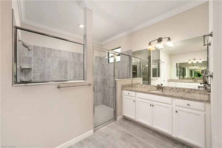 Bathroom featuring a shower with door, vanity, and ornamental molding