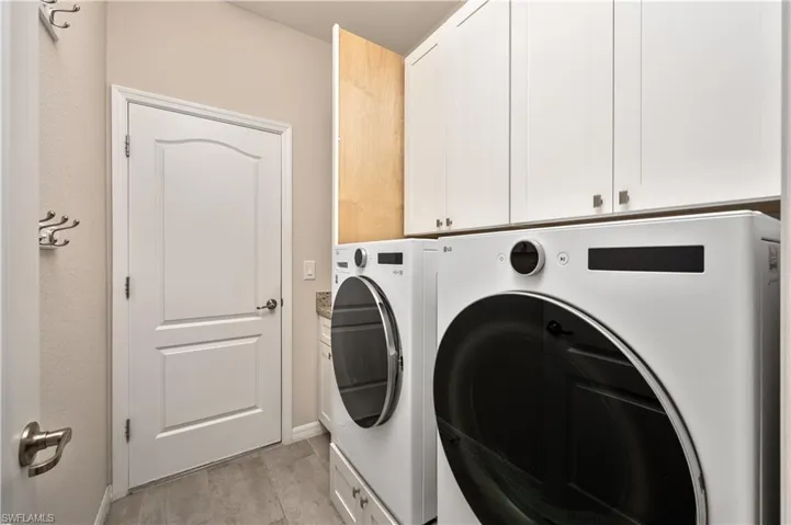 Laundry area with washing machine and dryer, light hardwood / wood-style flooring, and cabinets