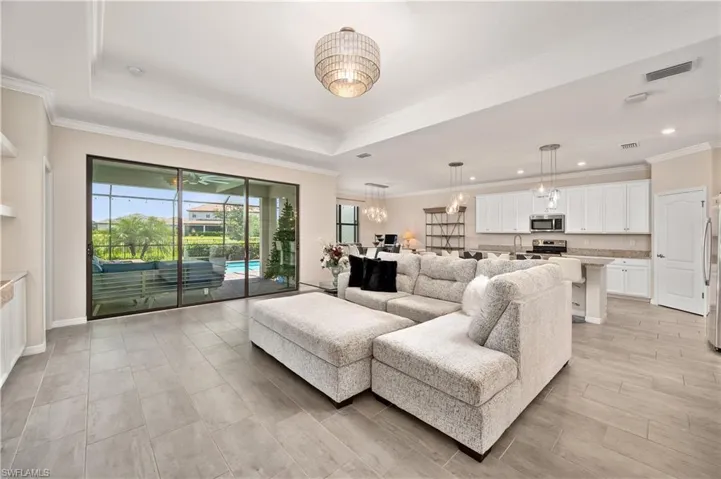 Living room with a raised ceiling, sink, and ornamental molding