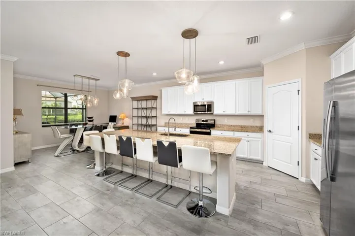 Kitchen featuring white cabinets, light stone counters, an island with sink, appliances with stainless steel finishes, and sink