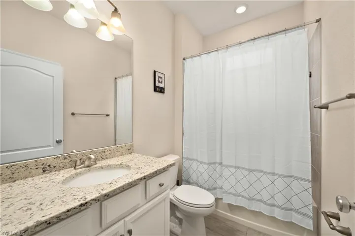Full bathroom with vanity, shower / bath combo, and toilet