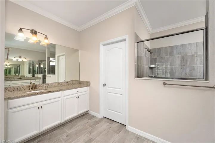 Bathroom with a shower, vanity, and crown molding