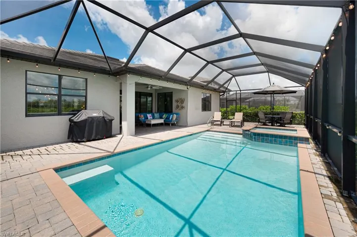 View of swimming pool featuring a patio area, outdoor lounge area, ceiling fan, an in ground hot tub, and glass enclosure