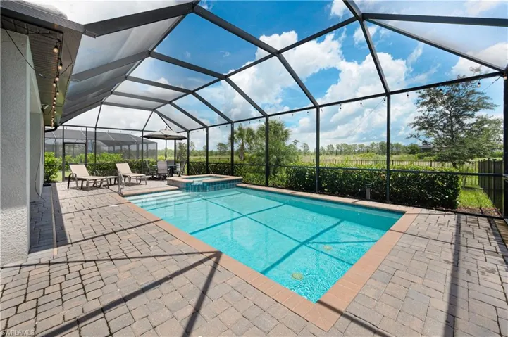 View of swimming pool featuring an in ground hot tub, a patio, and glass enclosure