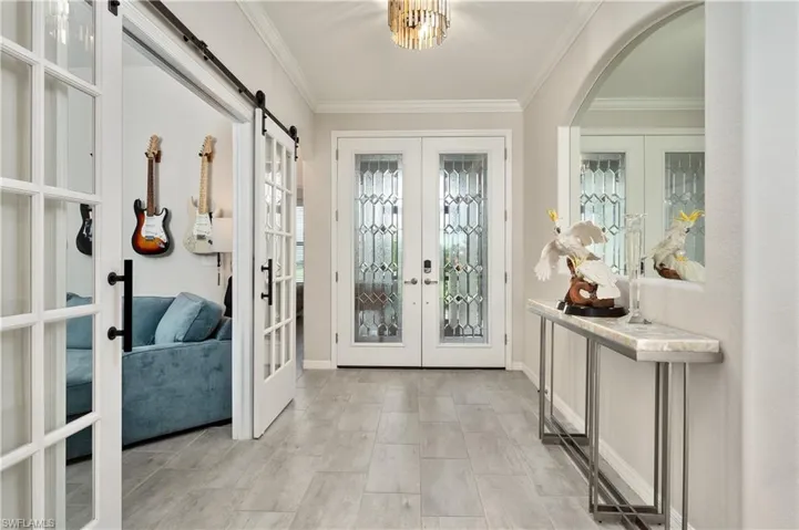 Entryway with crown molding, french doors, and a barn door