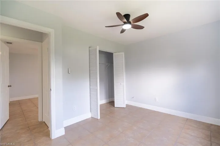 Neutral-toned room with tile flooring, light blue walls, and a ceiling fan with integrated lighting