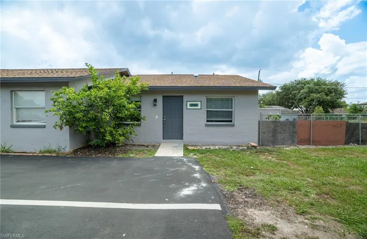 Exterior featuring a gray stucco finish, brown shingle roof, and a dark gray entry door