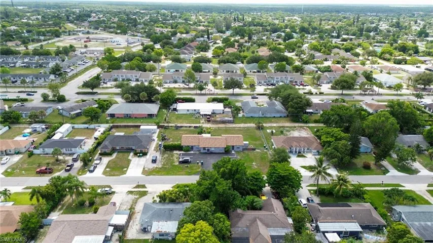 Aerial perspective showcasing a residential area with varied single-story homes, mature trees, and paved streets