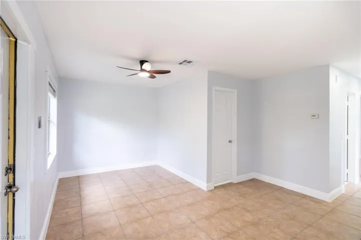 Bright interior space featuring light-colored walls, tile flooring, a ceiling fan with integrated lighting, and multiple windows